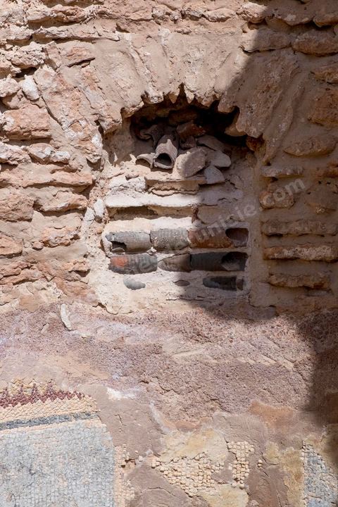 Thyna – l’antique Thaenae – est l’un des principaux sites archéologiques de la région de Sfax, situé à une douzaine de kilomètres au sud de la ville, sur le littoral tunisien. Ancienne cité punique, elle passe sous domination numide après la chute de Carthage en 146 av. J.-C., puis devient romaine en 46 av. J.-C. Élevée au rang de colonie au IIᵉ siècle, Thaenae connaît une importante prospérité durant l’époque romaine et reste occupée jusqu’à l’Antiquité tardive. Au IVᵉ siècle, la ville est protégée par une imposante enceinte de près de trois kilomètres, ponctuée de 84 tours et de trois portes. Aujourd’hui, le site conserve notamment les vestiges de ses remparts, de plusieurs établissements thermaux, dont les Thermes des Mois, de maisons antiques comme la Maison de Dionysos, ainsi que de vastes ensembles funéraires et nécropoles. Encore largement inexplorée, Thaenae fait aujourd’hui l’objet de nouvelles campagnes de recherches archéologiques et de valorisation.