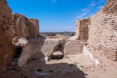Thyna – l’antique Thaenae – est l’un des principaux sites archéologiques de la région de Sfax, situé à une douzaine de kilomètres au sud de la ville, sur le littoral tunisien. Ancienne cité punique, elle passe sous domination numide après la chute de Carthage en 146 av. J.-C., puis devient romaine en 46 av. J.-C. Élevée au rang de colonie au IIᵉ siècle, Thaenae connaît une importante prospérité durant l’époque romaine et reste occupée jusqu’à l’Antiquité tardive. Au IVᵉ siècle, la ville est protégée par une imposante enceinte de près de trois kilomètres, ponctuée de 84 tours et de trois portes. Aujourd’hui, le site conserve notamment les vestiges de ses remparts, de plusieurs établissements thermaux, dont les Thermes des Mois, de maisons antiques comme la Maison de Dionysos, ainsi que de vastes ensembles funéraires et nécropoles. Encore largement inexplorée, Thaenae fait aujourd’hui l’objet de nouvelles campagnes de recherches archéologiques et de valorisation.