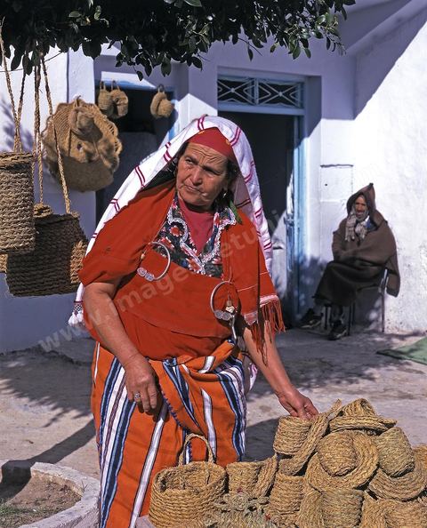 Femme en costume traditionnelle vendant des produits de la vannerie à Hergla