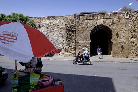 Enceinte de la medina et marchand avec parasol du Club Africain dans le quartier de Bab Djedid à Tunis.