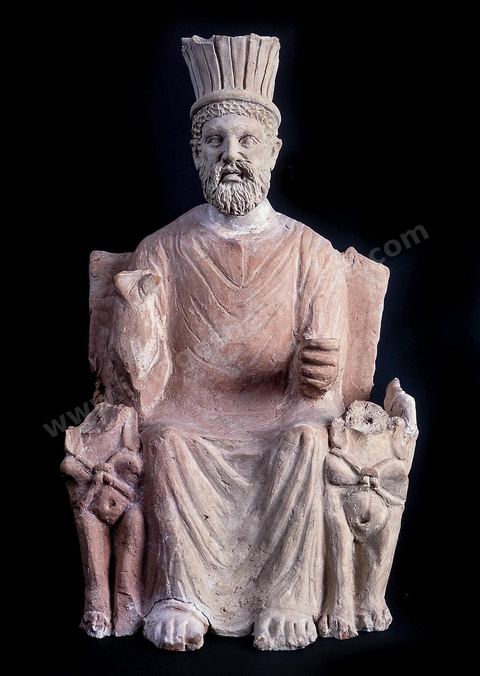 Statuette en terre cuite de Baal Hammon . Assis sur un trône dont les accoudoirs sont des sphinx, vêtu d’une longue tunique orientale et coiffé d’une tiare à plumes d’origine mésopo­tamienne, le dieu dégage une impression de gravité et de sérénité. Sa main droite est levée en signe de bénédiction (H.‑40‑cm, sanctuaire de Thinissut, ier‑ou‑iie‑siècle ap.‑J.-C., musée du Bardo). section punique - musée du Bardo
