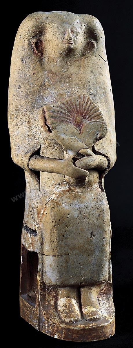 Statuette en terre cuite d’une déesse mère sur un trône à haut dossier, vêtue d’une longue robe, tenant un éventail en forme de palmette ( H.‑25‑cm, nécropole de Dermech, Carthage, VIIIe-VIIe siècles av. J.-C., musée du Bardo ). Section punique - musée du Bardo