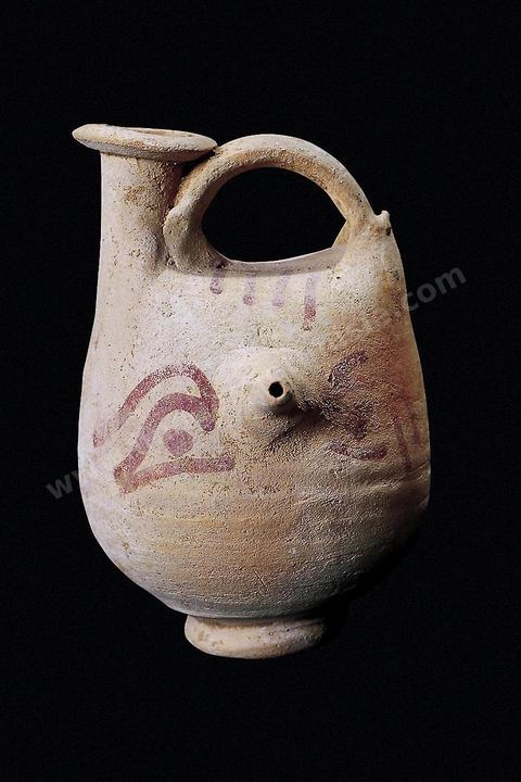 Vase biberon punique en terre cuite orné d’un masque humain peint où le nez fait fonction de tétine: forme et décor ont un rôle apotropaïque et sont censés protéger l’enfant contre les maléfices (H.‑11‑cm, nécropole punique de Carthage, IIIe‑siècle av.J.-C., musée du Bardo). section punique - musée du Bardo