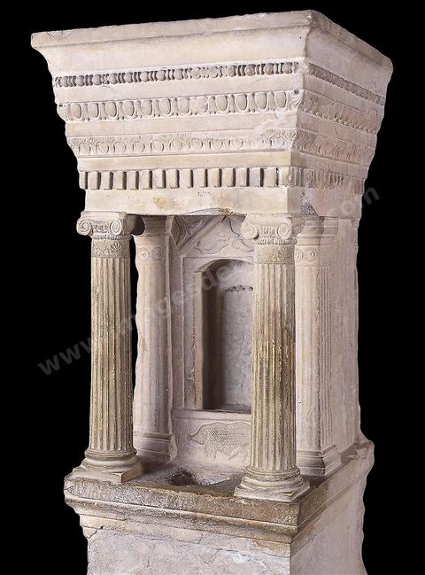 Ce petit édifice en calcaire ( naskos ) est probablement un modèle réduit d’un temple dédié à Déméter. Il se compose d’un socle sur lequel se dresse une cella dont la base est ornée d’un porc et le fronton de deux dauphins affrontés sous une fleur. Agrémentée de pilastres au style éolique, cette cella est précédée d’un porche à deux colonnettes ioniques d’une grande finesse d’exécution. L’entablement est remarquable par sa gorge égyptienne et la densité de son décor architectural fait de rangées de perles et de pirouettes, d’oves et de dards, de rais-de-cœur et de denticules ( H.‑117‑cm, l.‑48‑cm, ép.‑50‑cm, Thuburbo Majus, IIe siècle av. J.-C., musée du Bardo ). Section punique - musée du Bardo